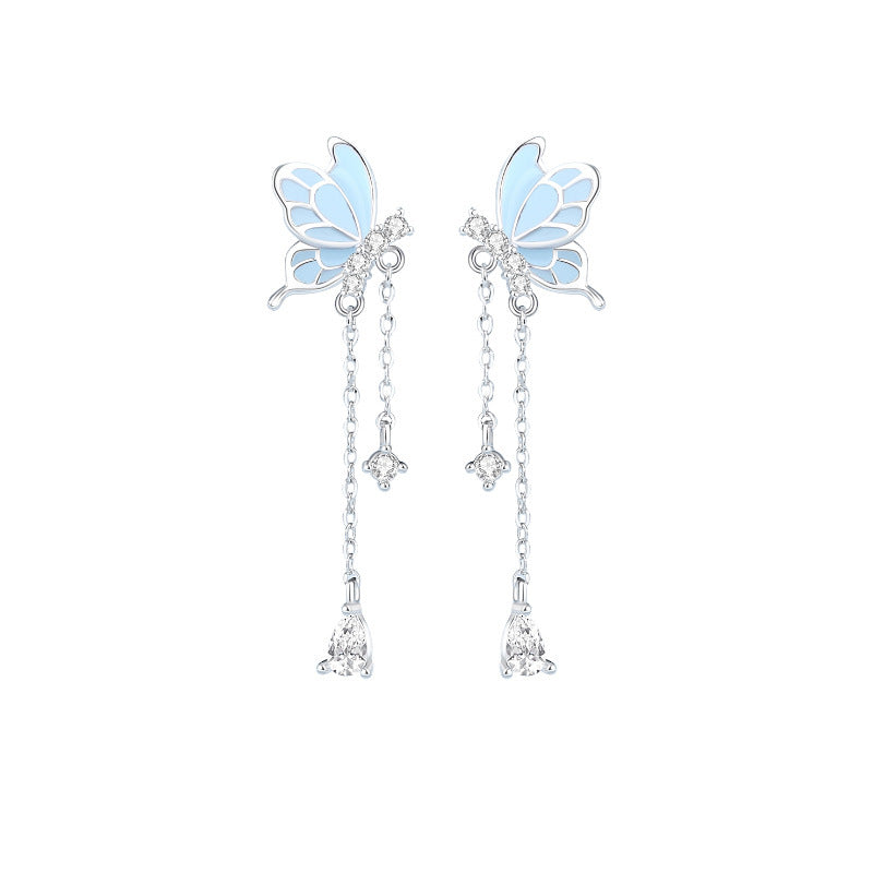 Butterfly-shaped earrings with dangling elements on a white background