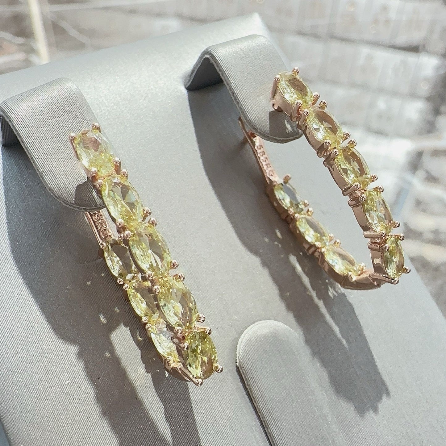 Pair of earrings with yellow gemstones on a gray stand