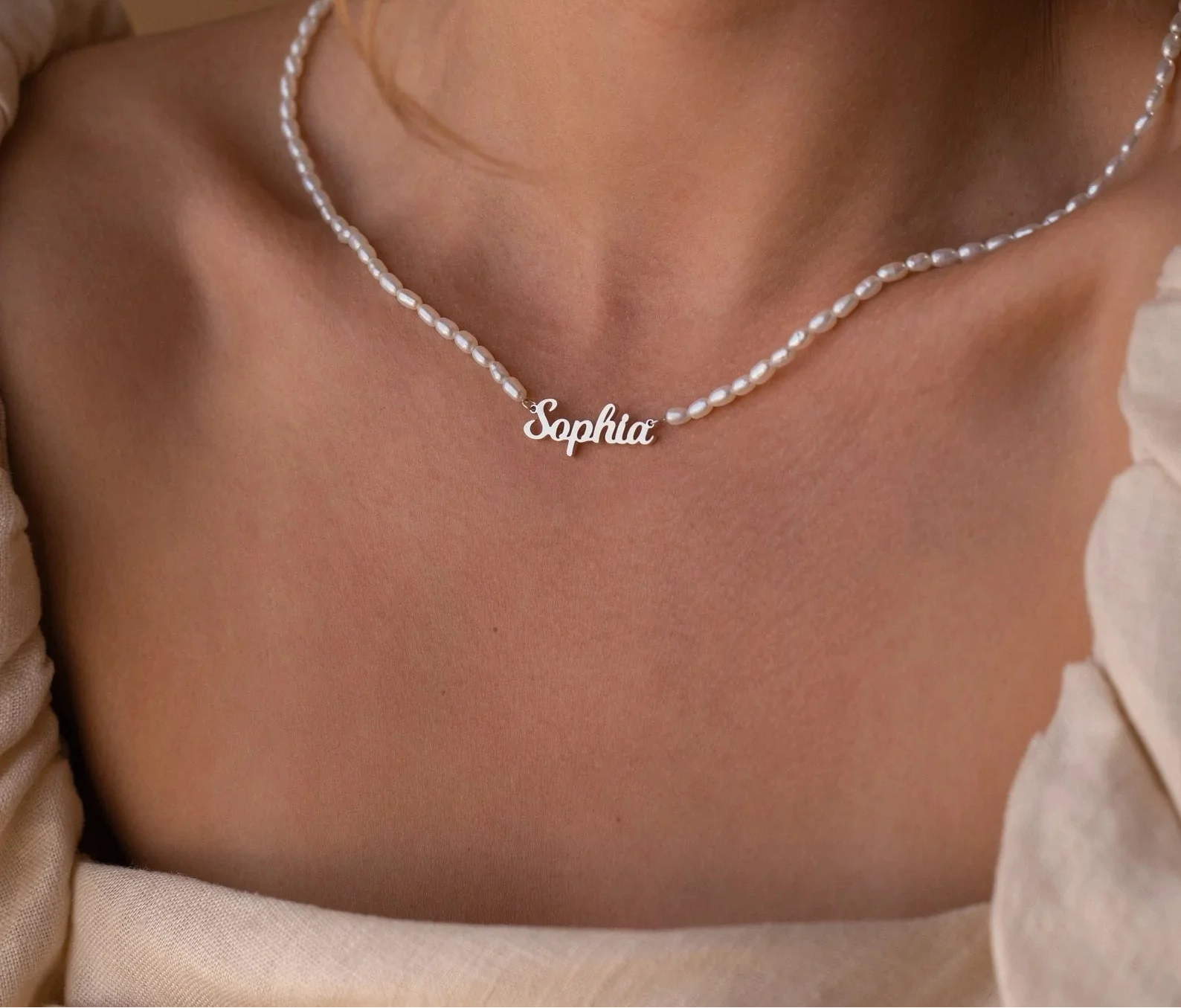 Necklace with 'Sophia' pendant on a person's neck against a neutral background